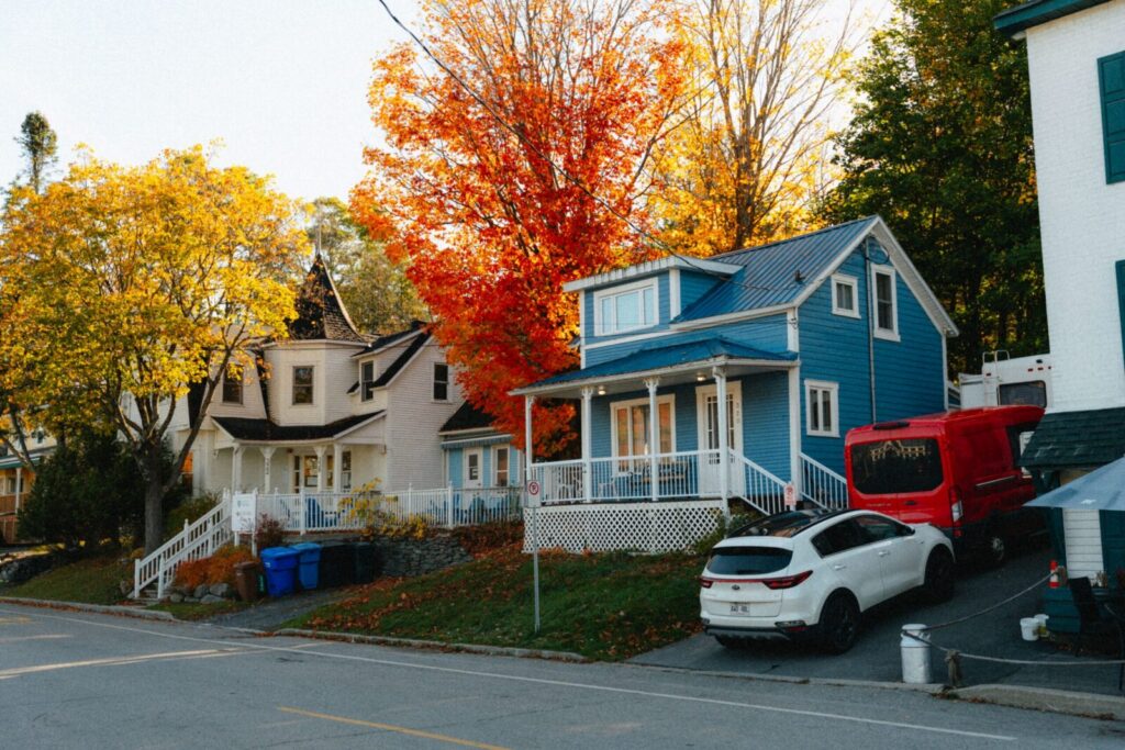Colorful houses surrounded by vibrant autumn foliage in North Hatley, Québec, Canada.