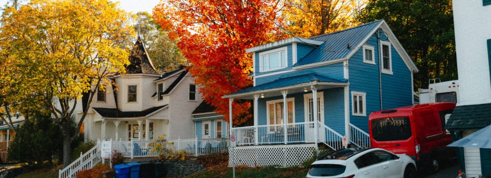 Colorful houses surrounded by vibrant autumn foliage in North Hatley, Québec, Canada.